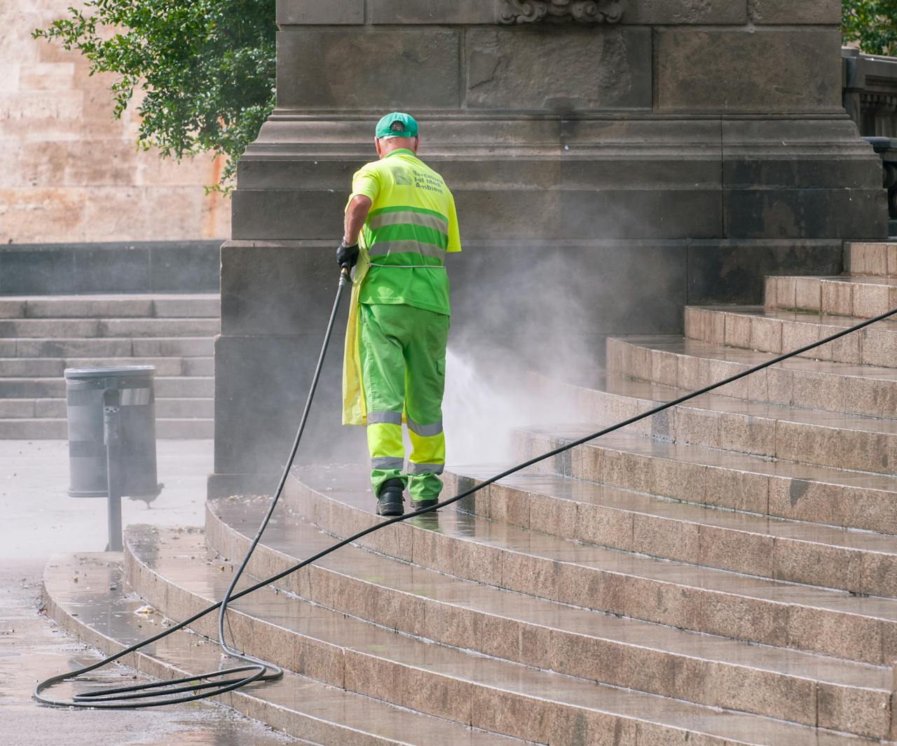 gallery-6 A municipal worker power washing stone steps outdoors, ensuring cleanliness and maintenance.